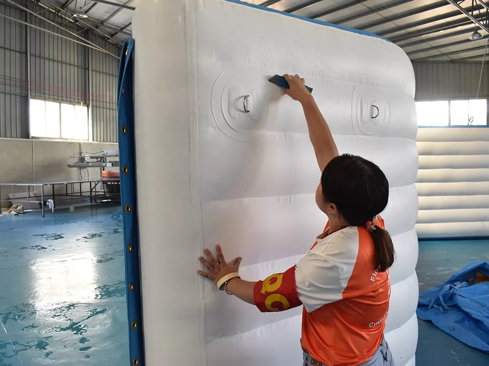 worker-inspecting-an-inflated-floating-obstacle-course-module-before-completion