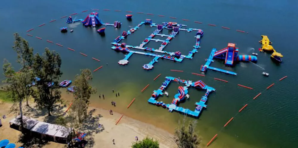 Circuito acuático hinchable con visitantes junto a la orilla de un lago