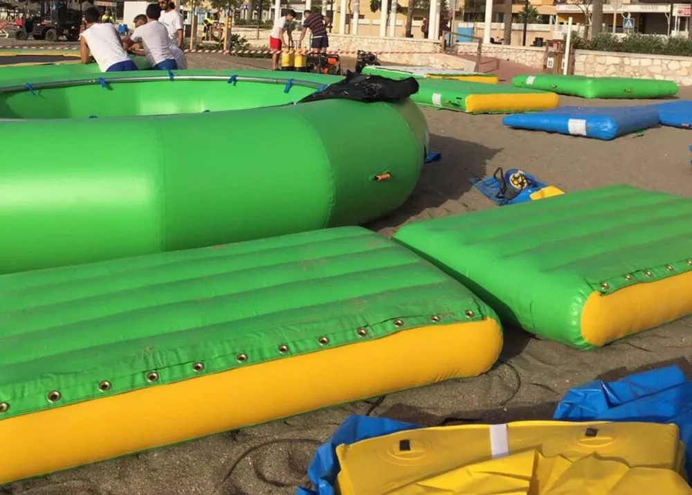 Trabajadores preparan los módulos de un circuito acuático hinchable en la playa